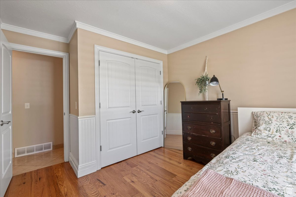Tiled bedroom featuring ornamental molding and a closet