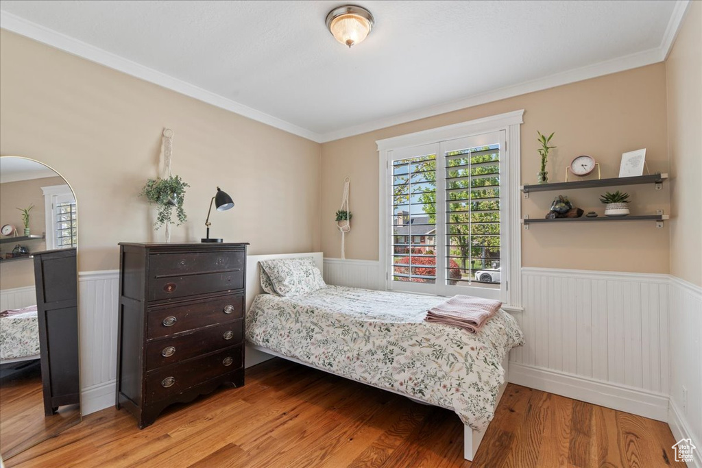 Bedroom with wood-type flooring and crown molding
