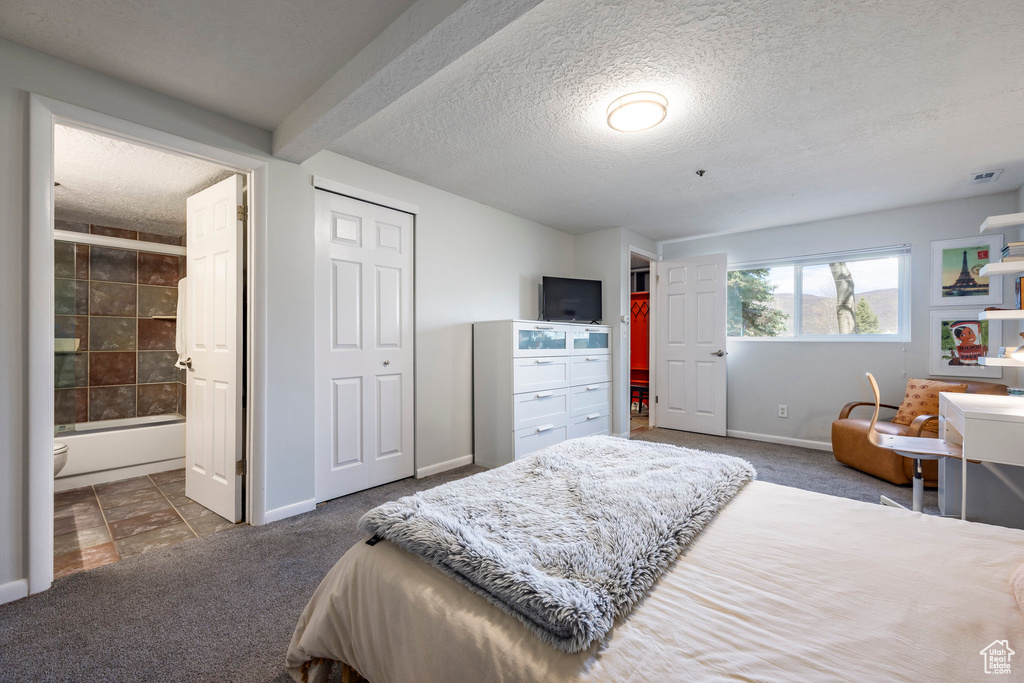 Bedroom with carpet flooring, a textured ceiling, and ensuite bathroom