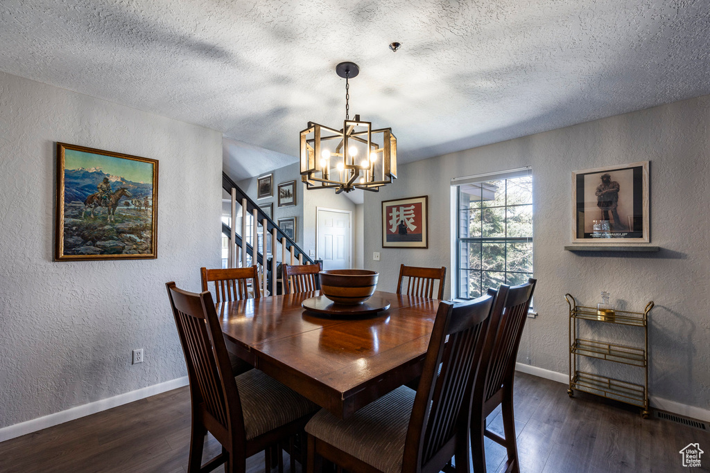 Dining room with dark hardwood / wood-style flooring, a notable chandelier, and a textured ceiling