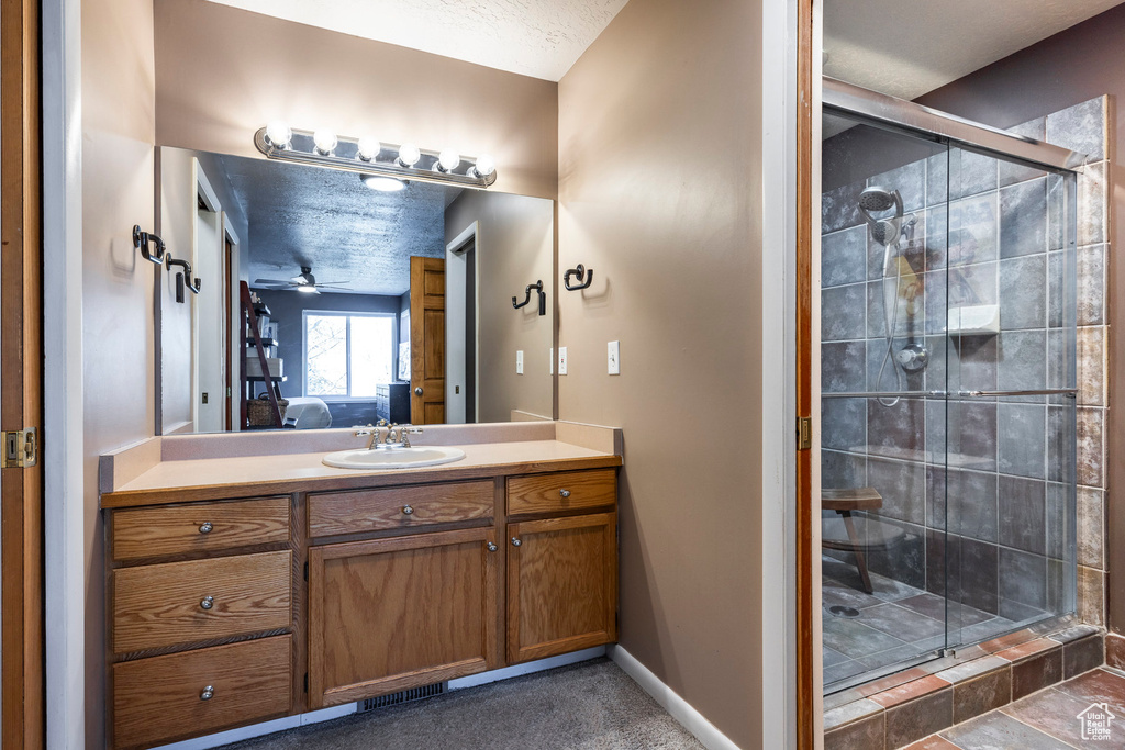 Bathroom featuring a shower with door, vanity, tile floors, and a textured ceiling