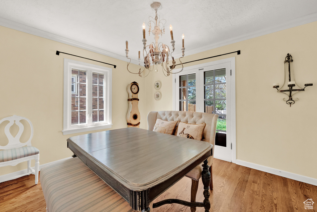Dining space with wood-type flooring, a notable chandelier, and ornamental molding