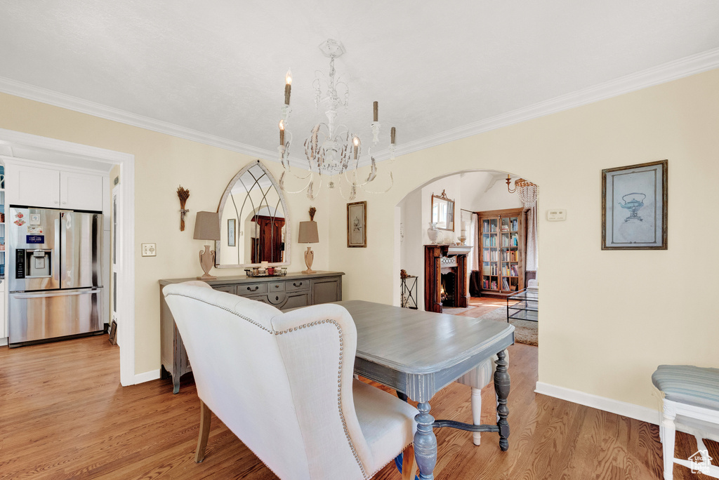 Dining room with light wood-type flooring, a chandelier, and ornamental molding