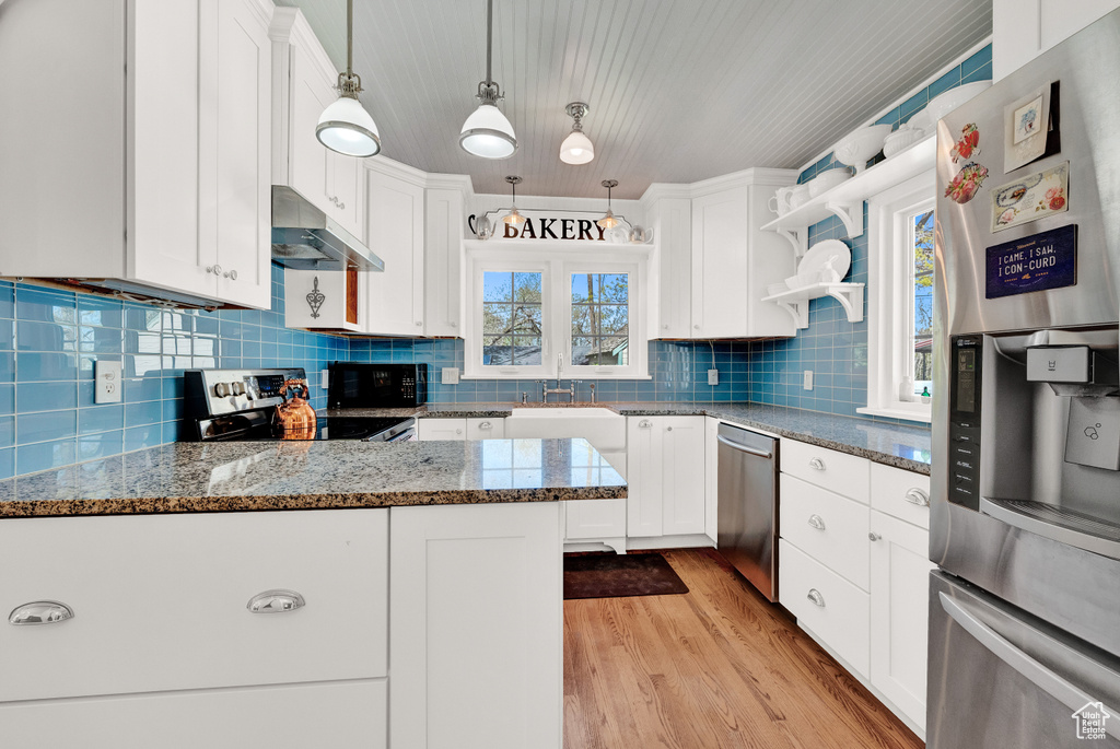 Kitchen featuring white cabinets, light hardwood / wood-style flooring, tasteful backsplash, and stainless steel appliances