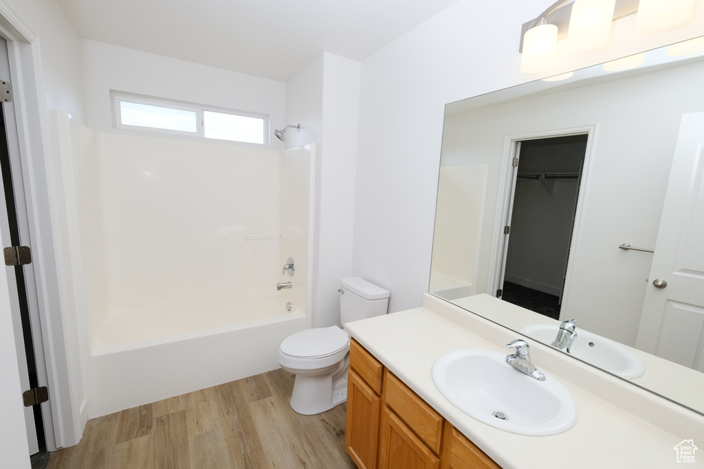 Full bathroom featuring wood-type flooring, vanity, toilet, and washtub / shower combination