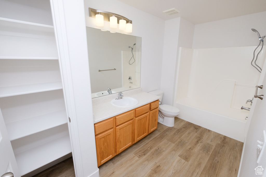 Full bathroom with hardwood / wood-style flooring, tub / shower combination, toilet, and vanity with extensive cabinet space