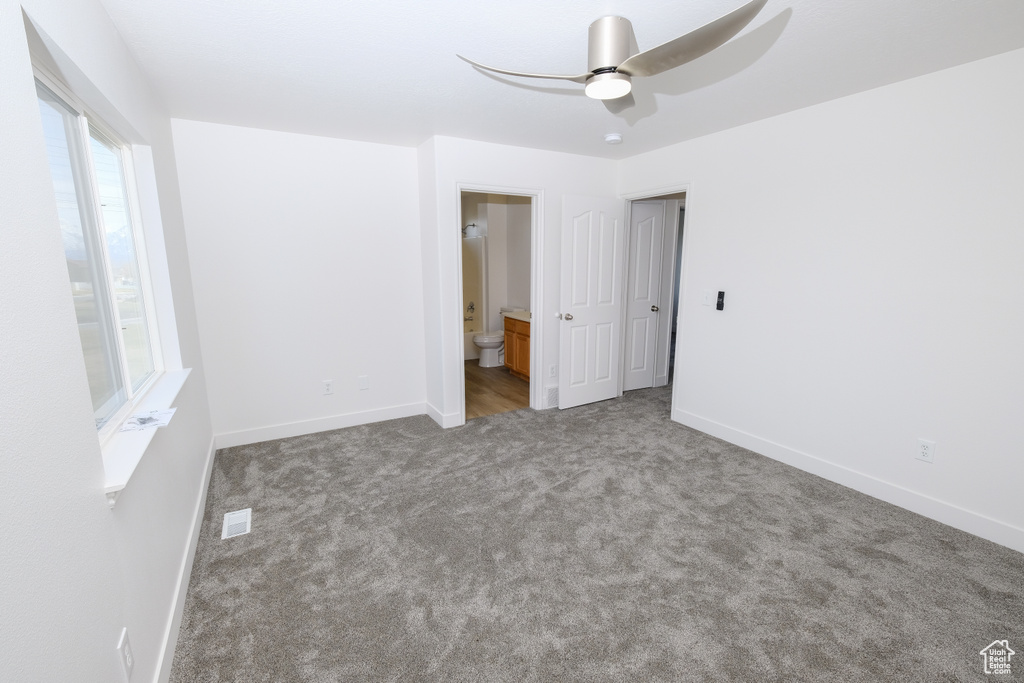 Unfurnished bedroom featuring ceiling fan, carpet floors, and ensuite bathroom