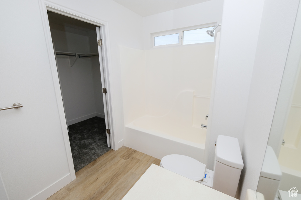 Bathroom featuring shower / washtub combination, hardwood / wood-style flooring, and toilet
