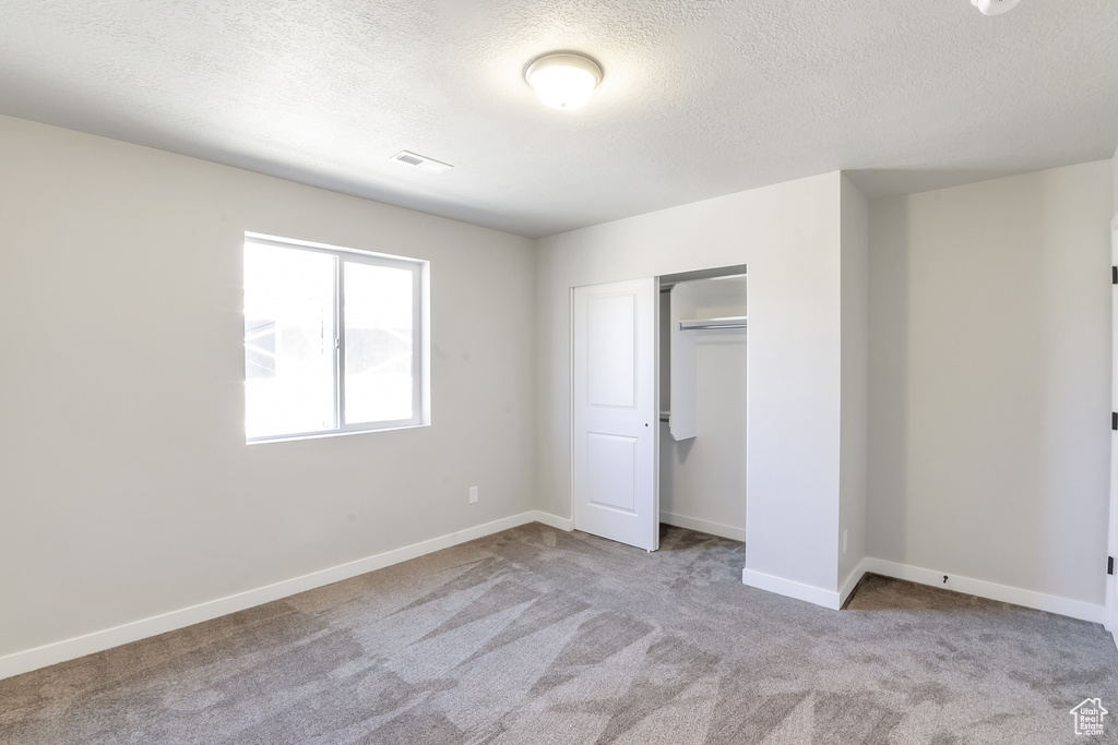 Unfurnished bedroom with a closet, carpet, and a textured ceiling