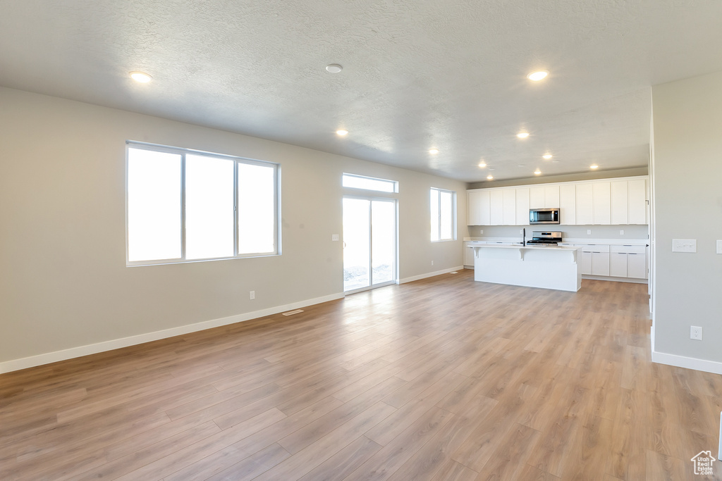 Unfurnished living room with light hardwood / wood-style flooring and a textured ceiling
