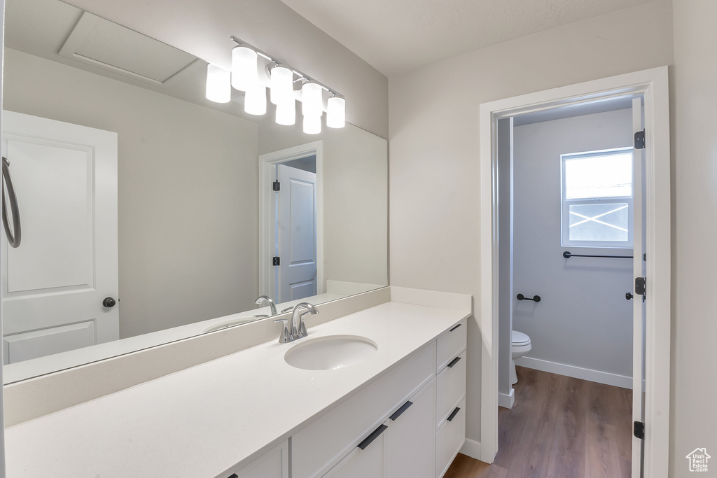 Bathroom featuring hardwood / wood-style flooring, toilet, and vanity