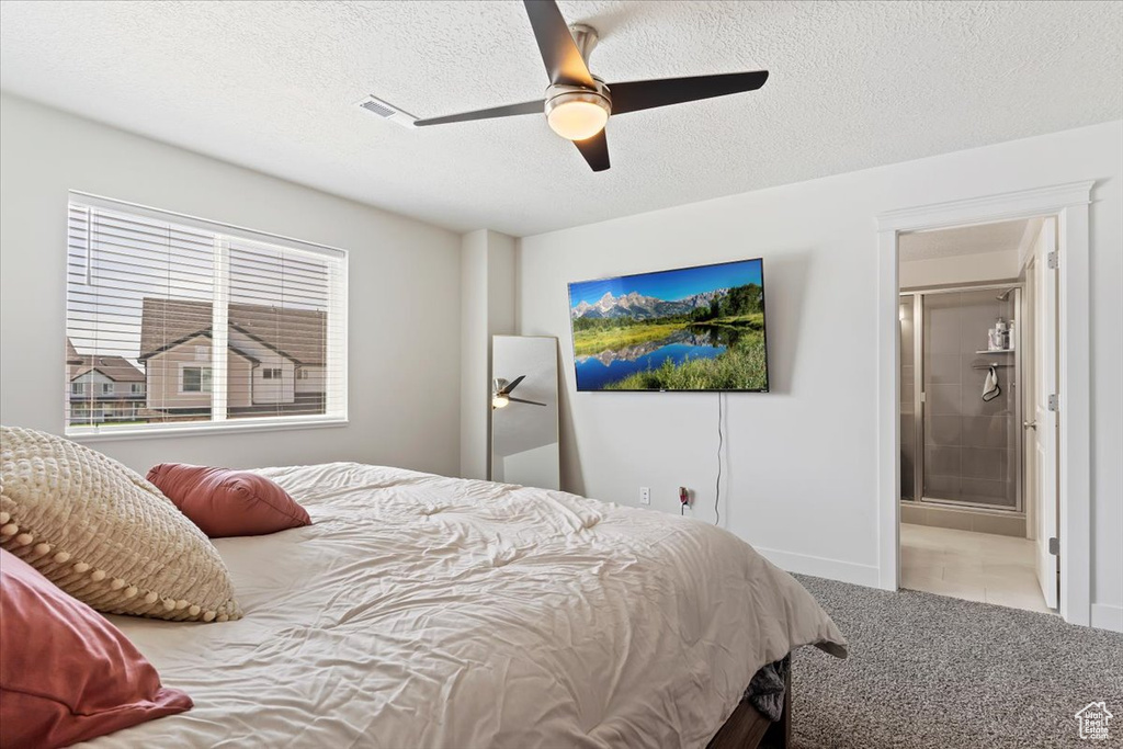 Bedroom with a textured ceiling, ceiling fan, light carpet, and ensuite bathroom
