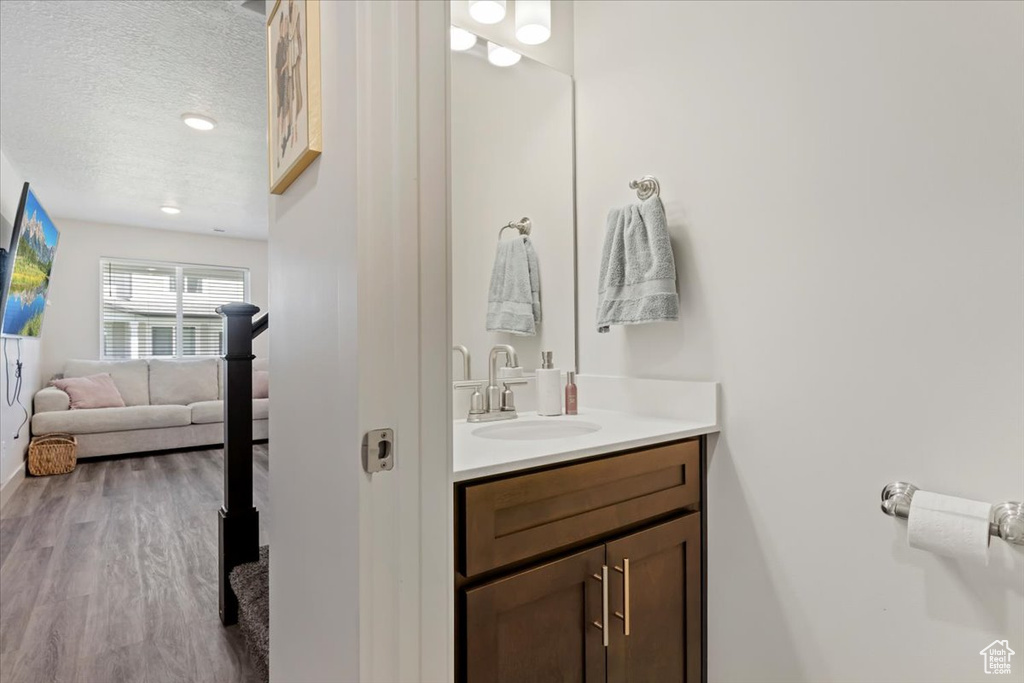 Bathroom with a textured ceiling, hardwood / wood-style floors, and vanity