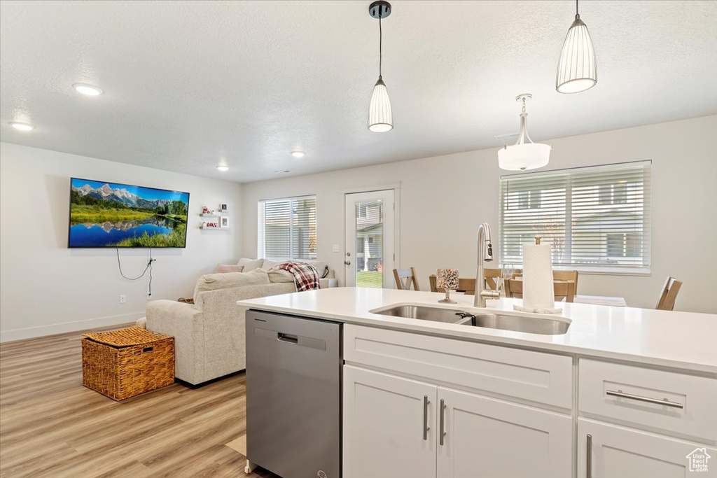Kitchen featuring hanging light fixtures, white cabinets, light hardwood / wood-style flooring, sink, and dishwasher
