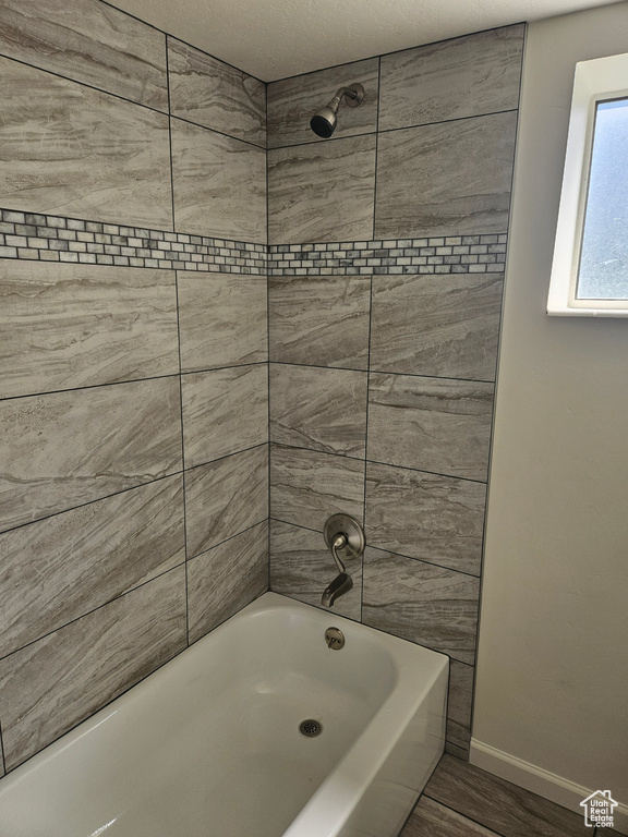 Bathroom with tiled shower / bath combo and a textured ceiling