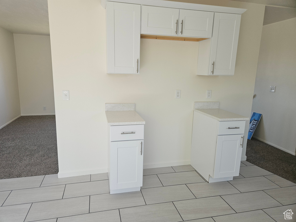 Kitchen with white cabinets and light tile flooring