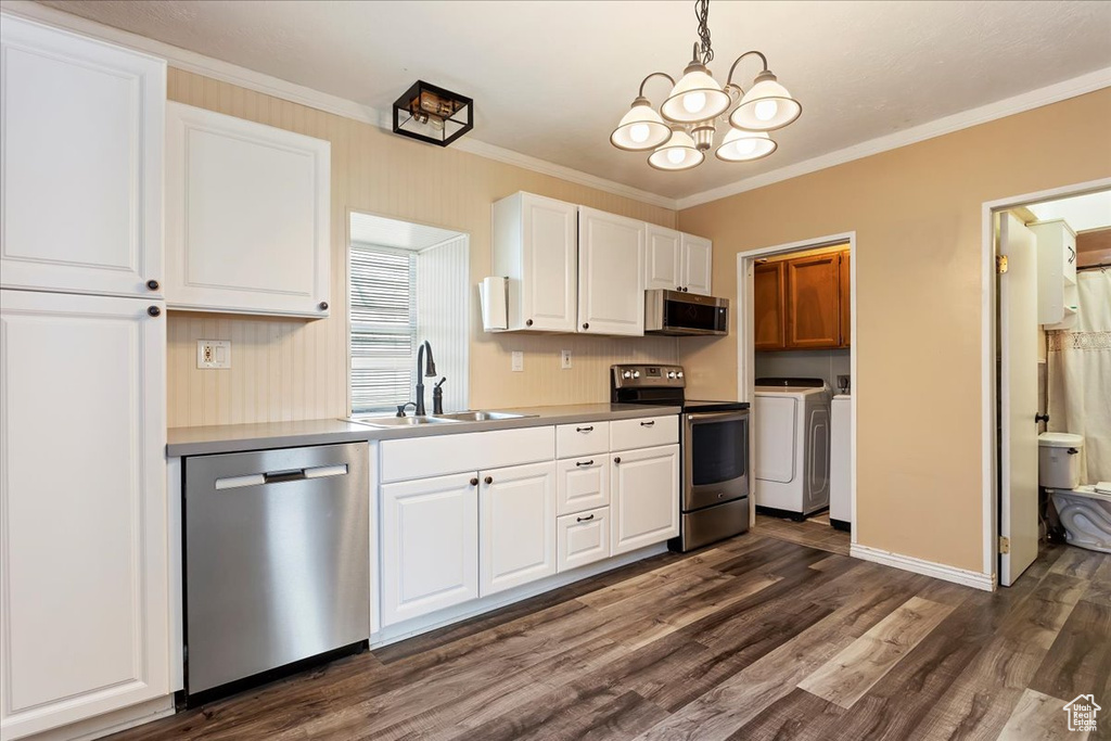 Kitchen with appliances with stainless steel finishes, sink, hanging light fixtures, dark hardwood / wood-style floors, and separate washer and dryer