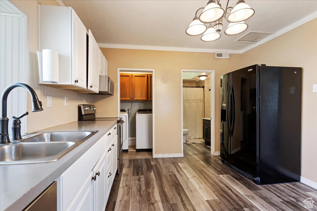 Kitchen featuring black fridge with ice dispenser, crown molding, independent washer and dryer, hardwood / wood-style flooring, and white cabinets