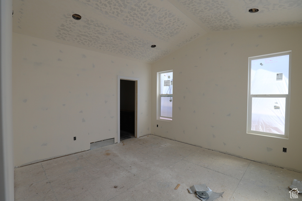 Empty room featuring lofted ceiling