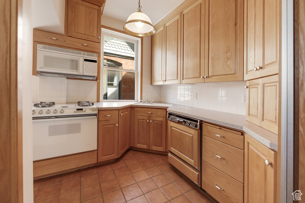 Kitchen with tile flooring, sink, white appliances, tasteful backsplash, and pendant lighting
