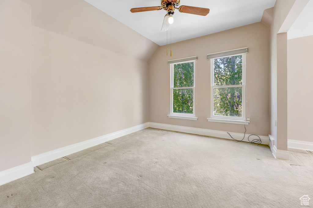 Spare room featuring ceiling fan, carpet floors, and lofted ceiling
