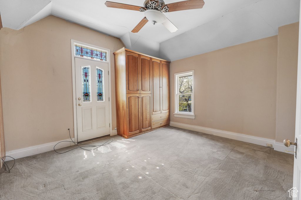 Unfurnished bedroom with light colored carpet, lofted ceiling, and ceiling fan