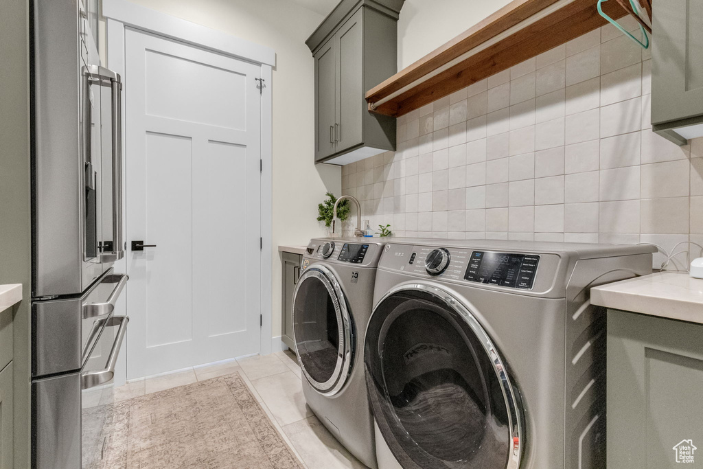 Laundry room with cabinets, washer and dryer, and light tile floors