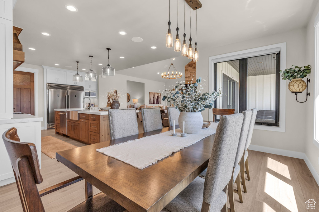 Dining space with light hardwood / wood-style flooring and an inviting chandelier