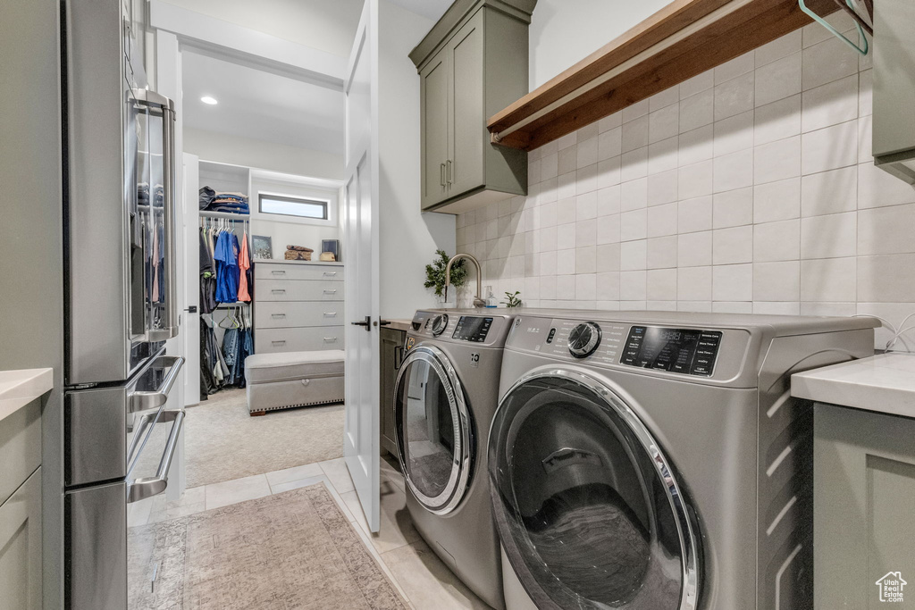 Washroom featuring cabinets, light tile flooring, and washing machine and clothes dryer
