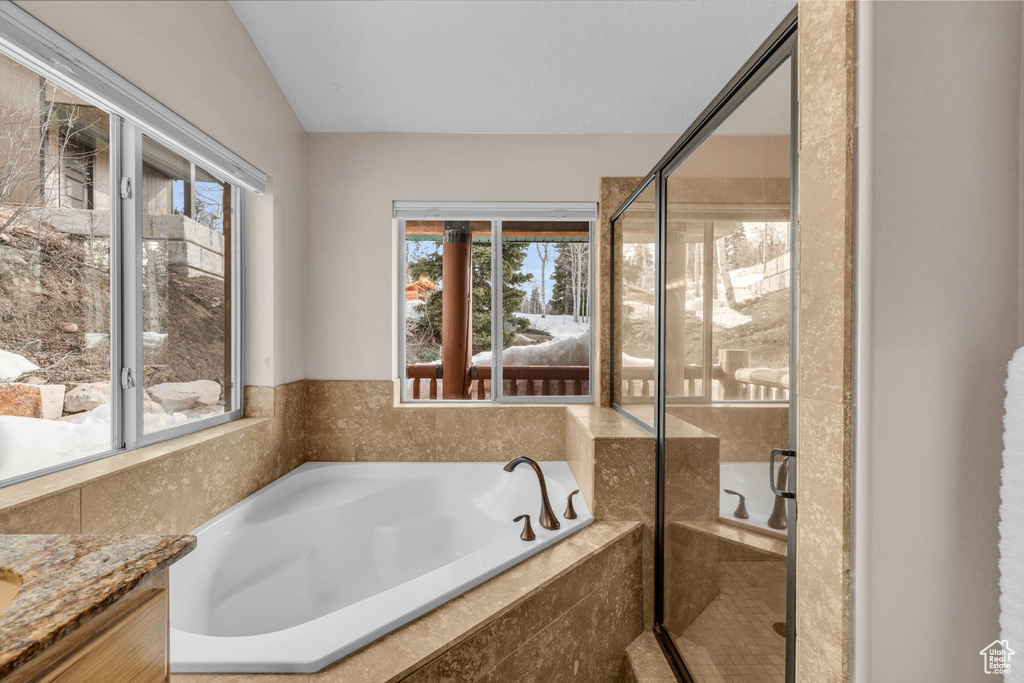 Bathroom featuring vaulted ceiling, vanity, and separate shower and tub