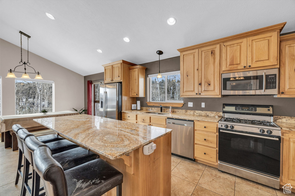 Kitchen featuring a kitchen island, a kitchen breakfast bar, light tile floors, and stainless steel appliances