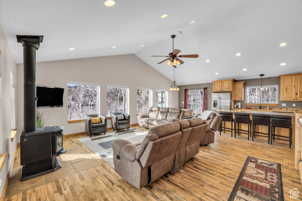 Living room featuring light hardwood / wood-style floors, a healthy amount of sunlight, ceiling fan, and a wood stove