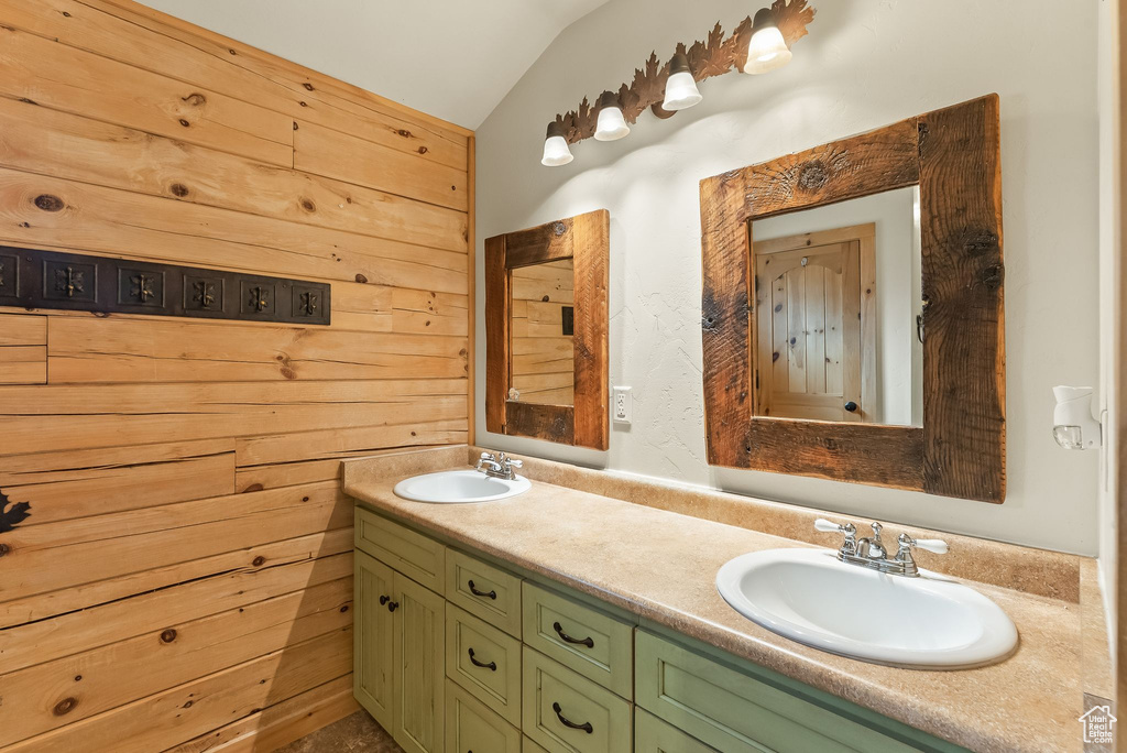 Bathroom with wood walls, vaulted ceiling, and dual vanity