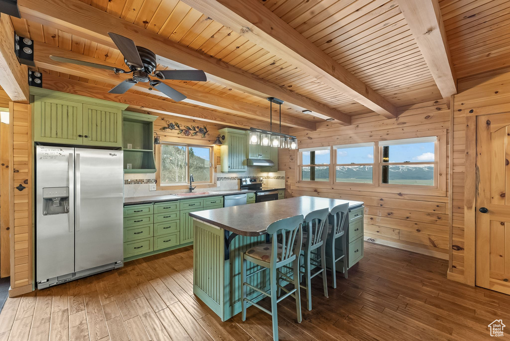 Kitchen with wood walls, appliances with stainless steel finishes, dark wood-type flooring, and green cabinets