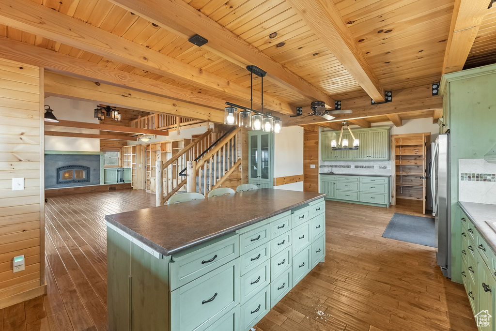 Kitchen with decorative light fixtures, hardwood / wood-style flooring, wood ceiling, beam ceiling, and a kitchen island