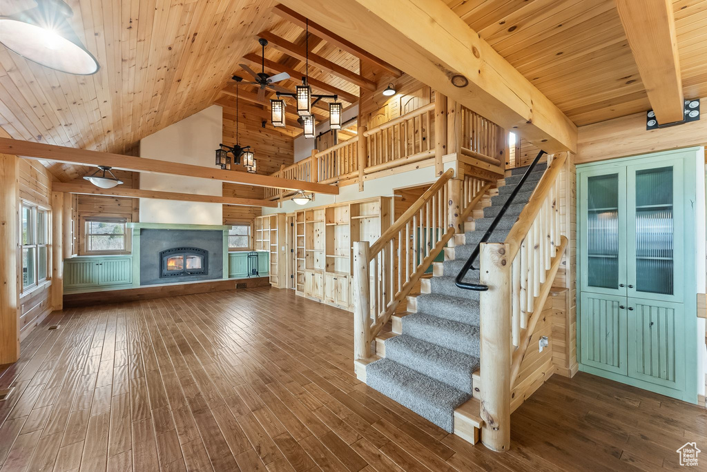 Staircase featuring wooden walls, wooden ceiling, ceiling fan, and hardwood / wood-style floors