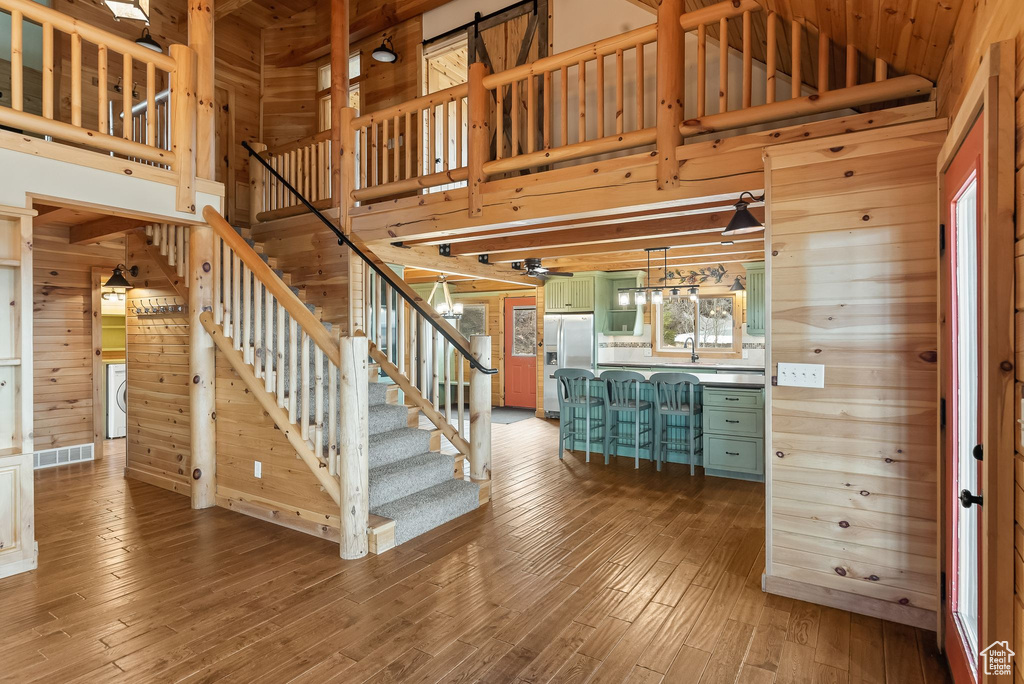 Stairs featuring hardwood / wood-style flooring, wood walls, a towering ceiling, and sink
