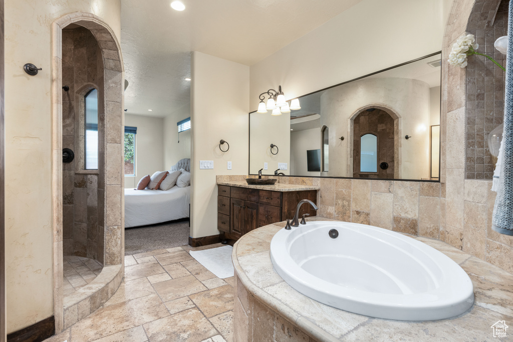 Bathroom with tile walls, tile floors, independent shower and bath, and large vanity