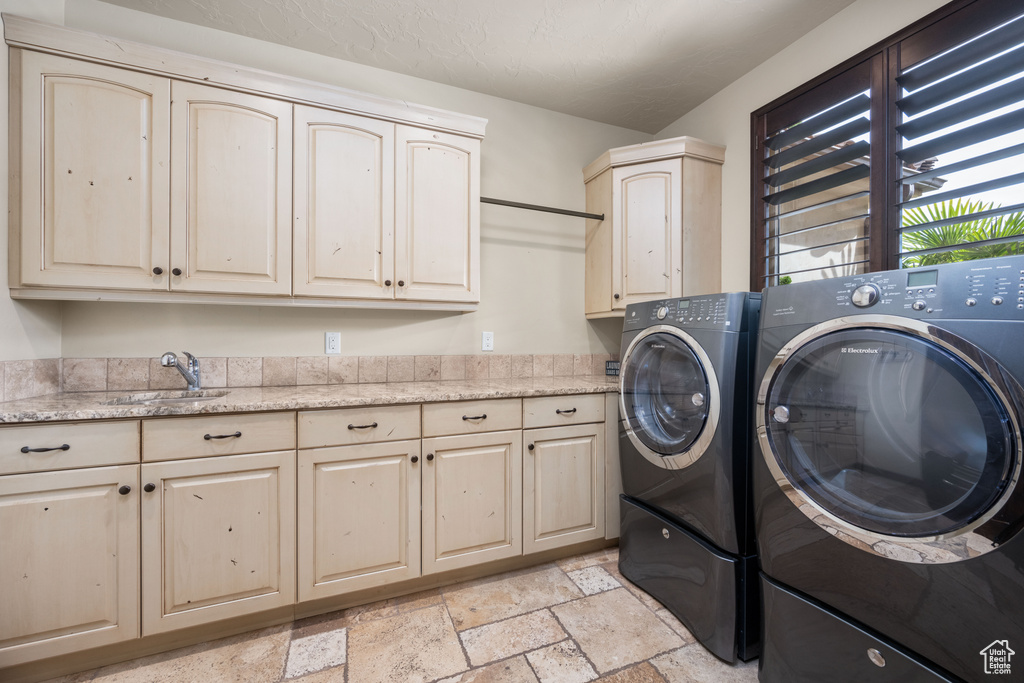 Laundry room with cabinets, sink, light tile flooring, and washer and dryer