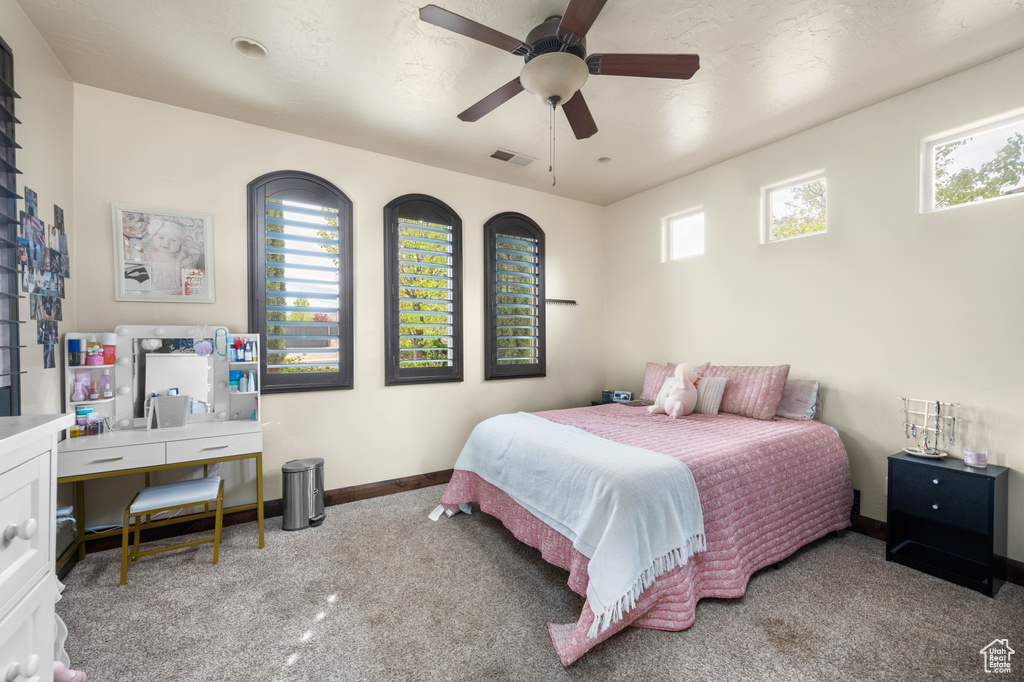 Bedroom with ceiling fan, carpet floors, and multiple windows