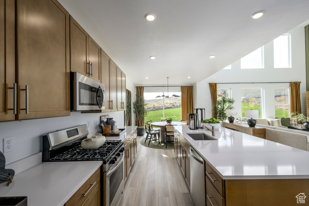 Kitchen featuring a healthy amount of sunlight, sink, stainless steel appliances, and a center island with sink