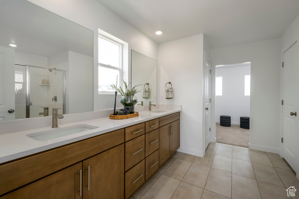 Bathroom with double sink vanity, a shower with shower door, and tile flooring
