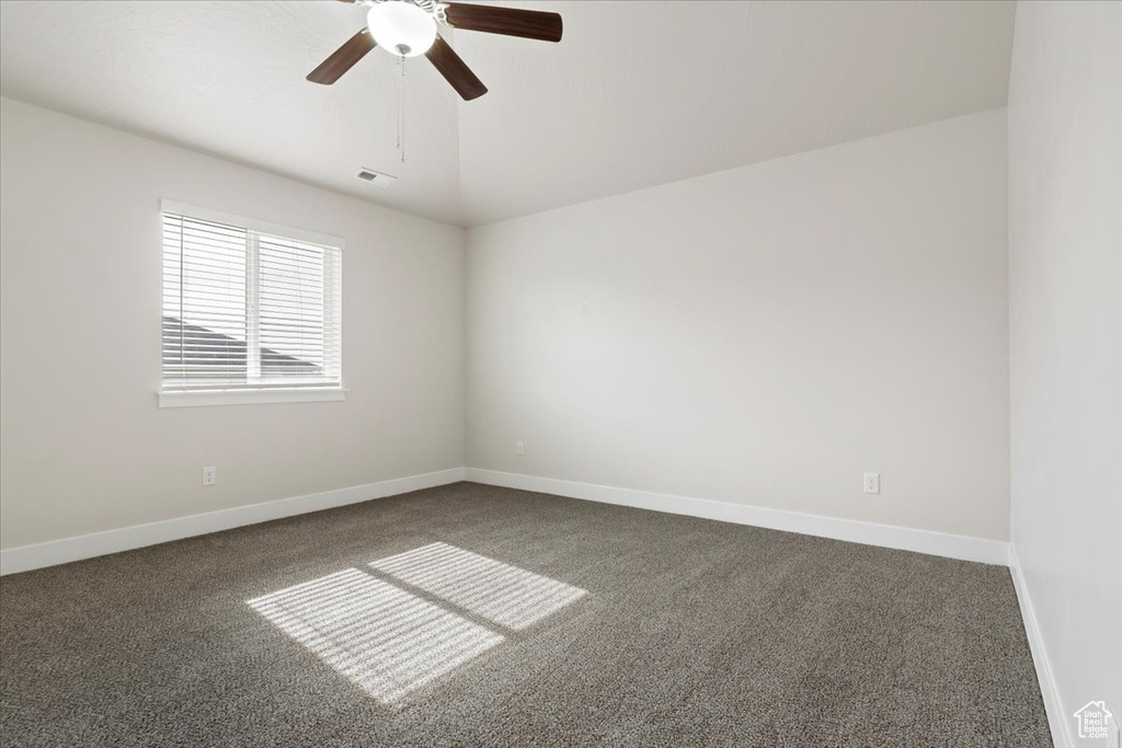 Unfurnished room with lofted ceiling, ceiling fan, and dark colored carpet