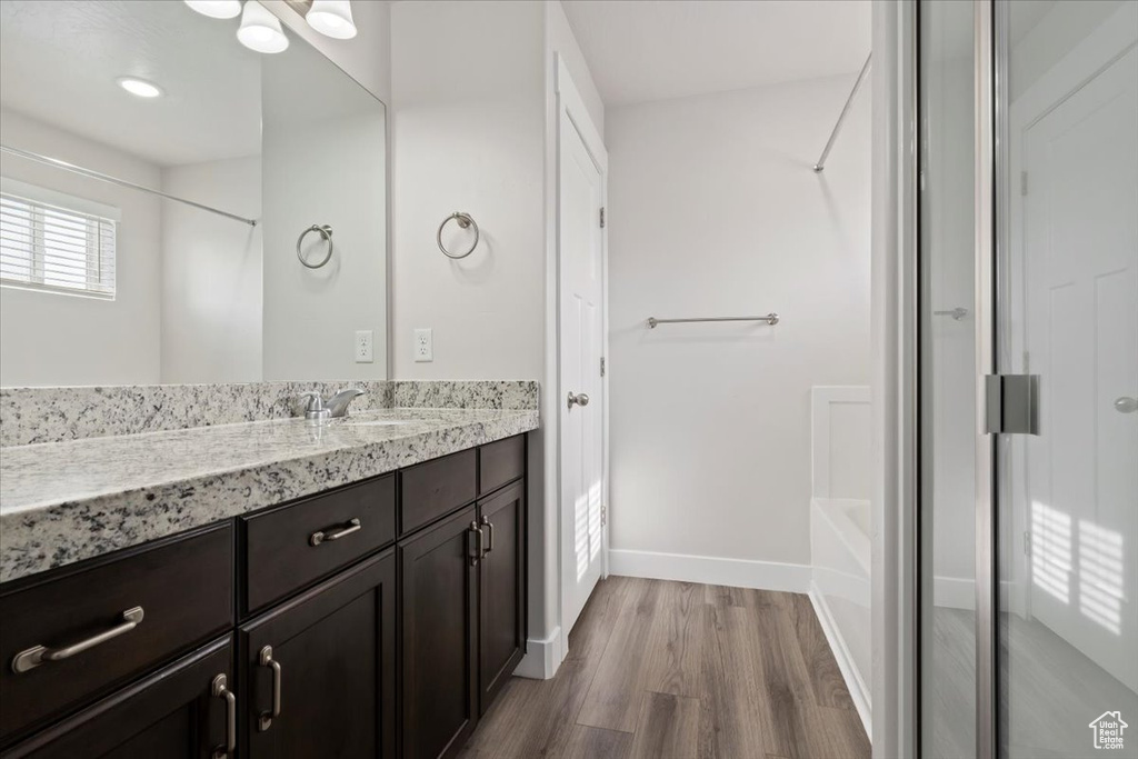 Bathroom featuring shower / bath combination, large vanity, and hardwood / wood-style flooring