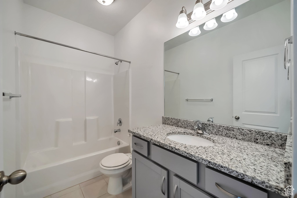 Full bathroom with tile flooring, shower / bathing tub combination, vanity with extensive cabinet space, and toilet