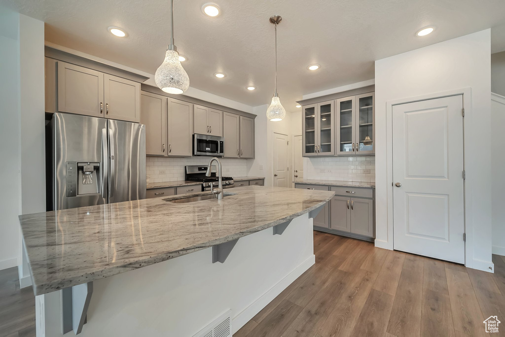 Kitchen with backsplash, sink, stainless steel appliances, and wood-type flooring