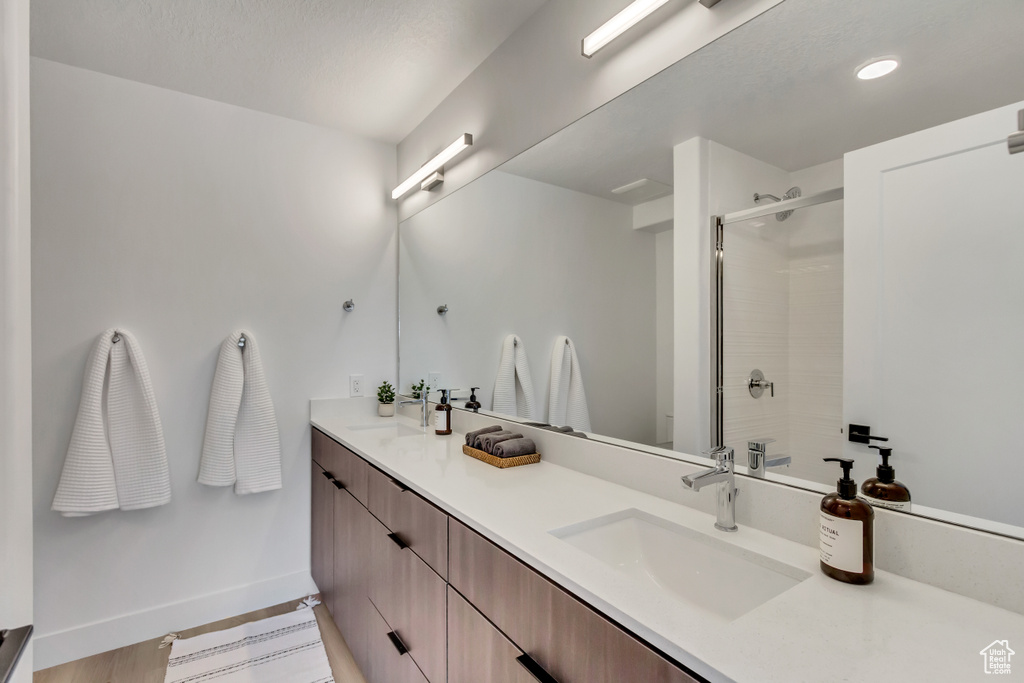 Bathroom featuring hardwood / wood-style floors, walk in shower, and dual bowl vanity