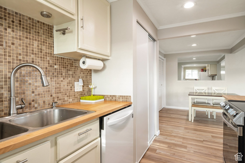Kitchen with tasteful backsplash, light hardwood / wood-style flooring, crown molding, and white appliances