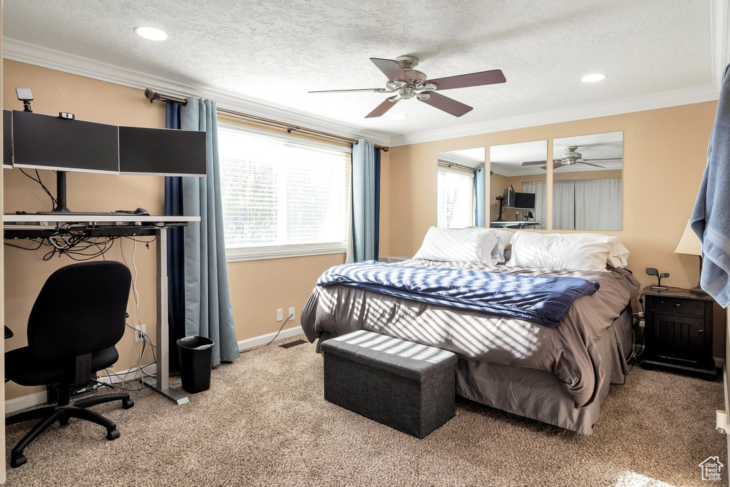 Bedroom featuring light colored carpet, a textured ceiling, ceiling fan, and crown molding