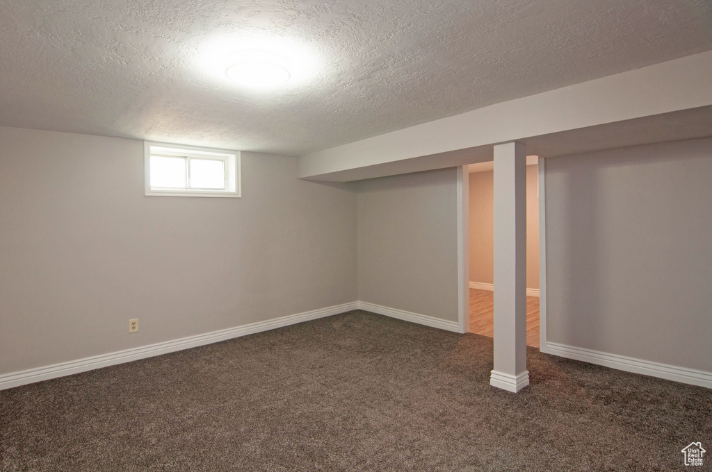 Basement with dark carpet and a textured ceiling